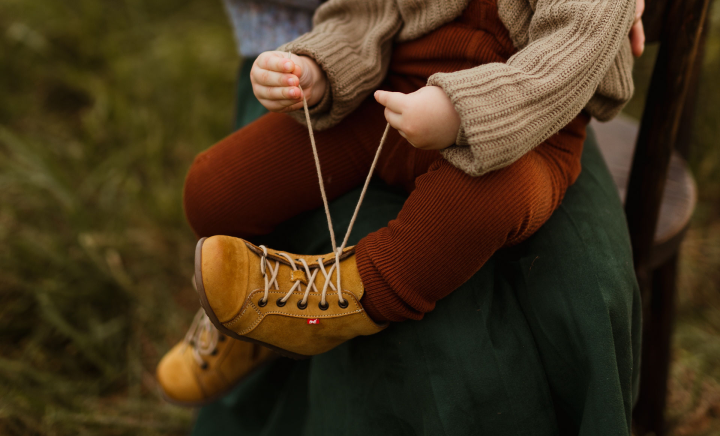 Dziecko wiąże buta na kolanach mamy